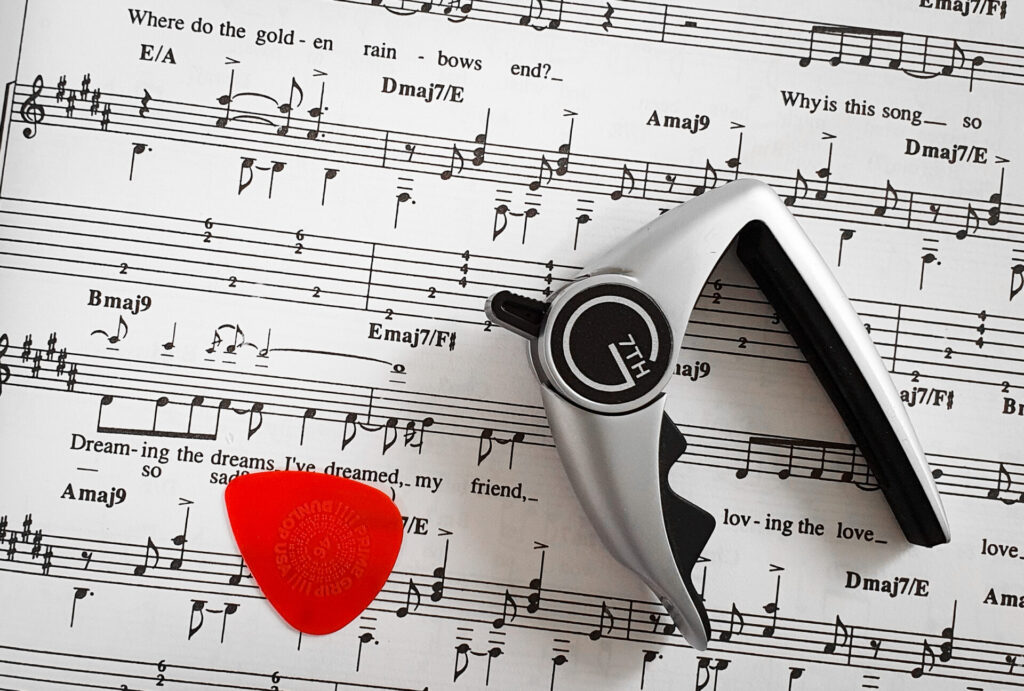 Guitar capo and pick on sheet music