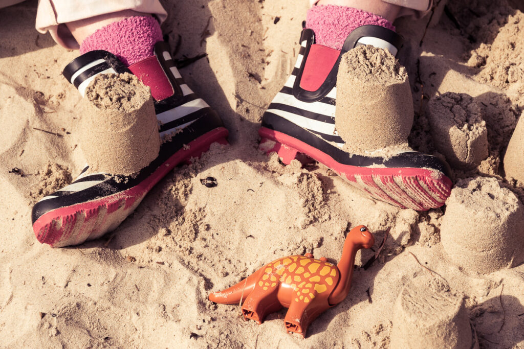 Sandcastles built on a child's foot in wellys