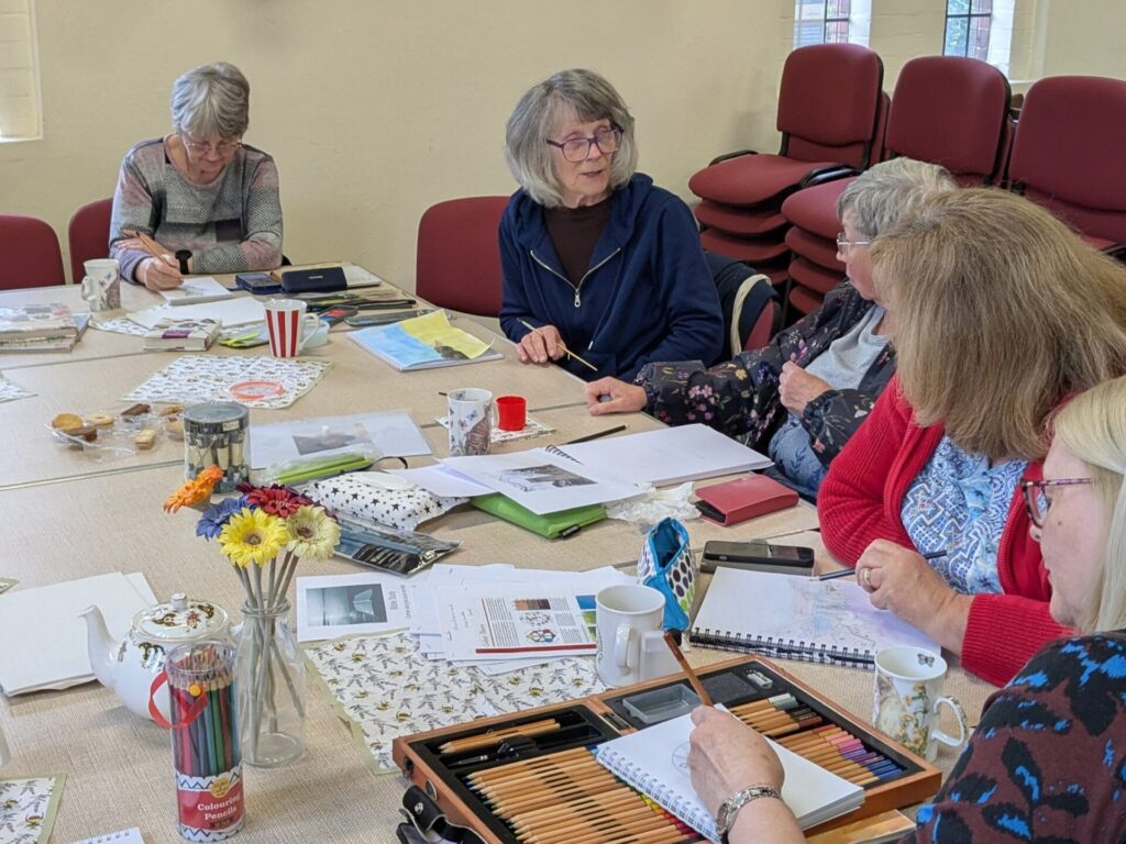 Group of members at the Sketching Group sat around a table