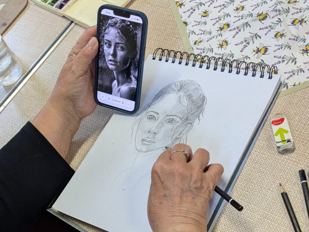 Artist sketching a portrait taken from a phone